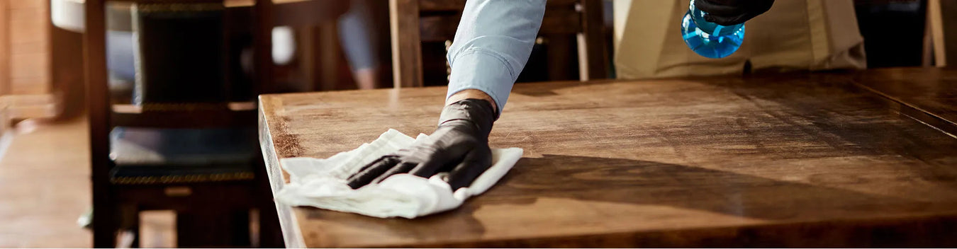 Hand wiping a wood counter with a white bar mop towel